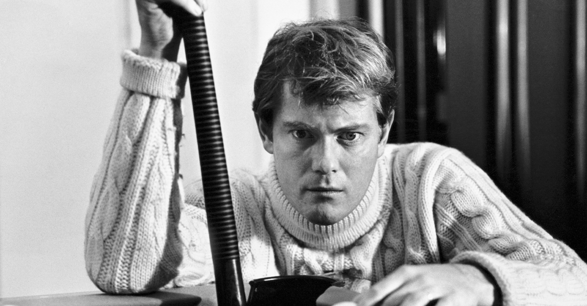 View of American actor Troy Donahue (1936 - 2001), a pool cue in one hand and a cue ball on the other, as he crouches down at the corner of a pool table, Beverly Hills, California, 1966.