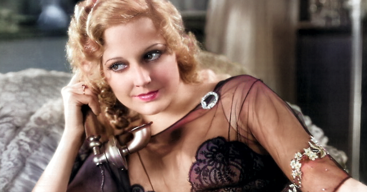 Colorized image of Thelma Todd in a black lacy outfit holding an old phone to her ear.