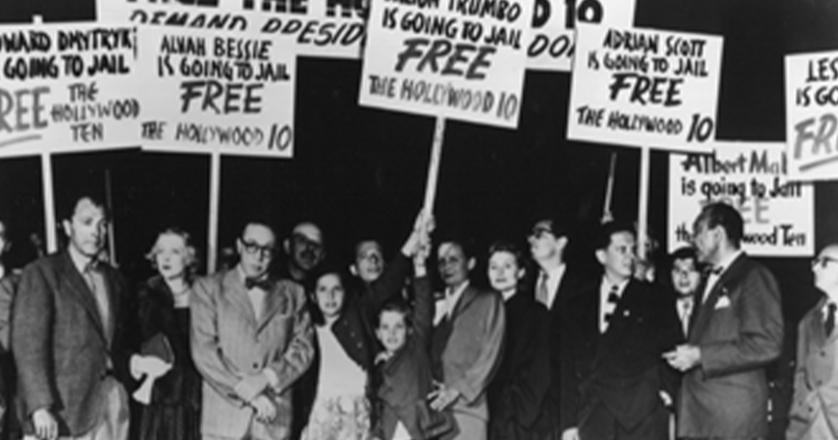 Screenshot from the documentary film Legacy of the Hollywood Blacklist (1987) consisting of 1950 image showing protestors opposing the jailing of the Hollywood Ten