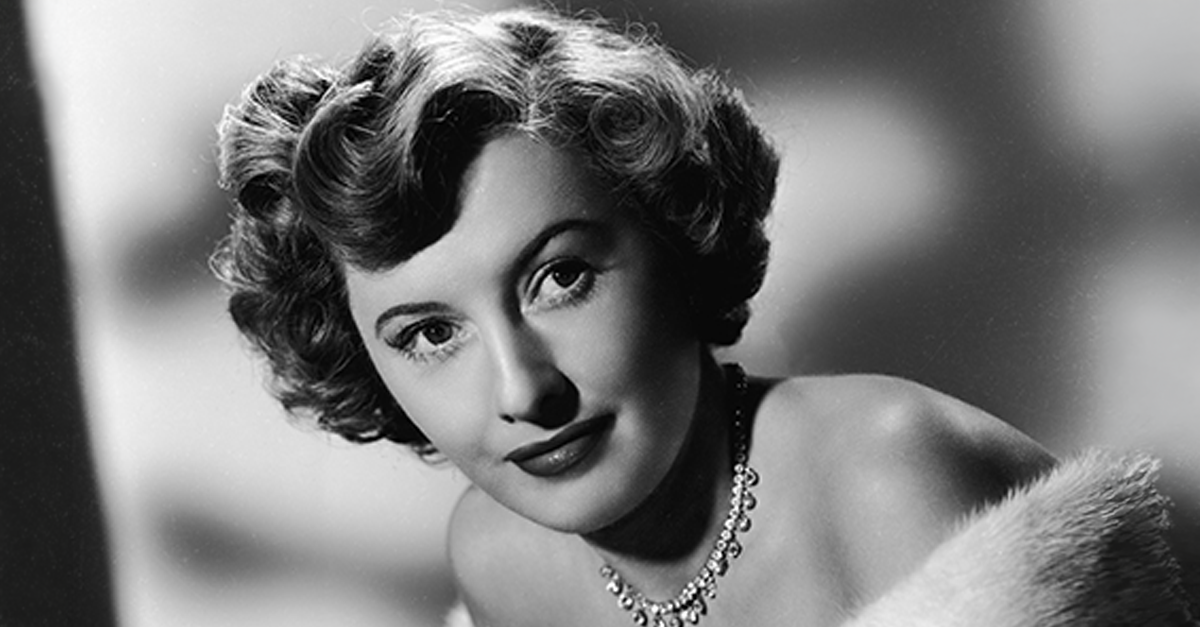 Studio portrait of actor Barbara Stanwyck wearing a fur coat and diamond necklace,1949